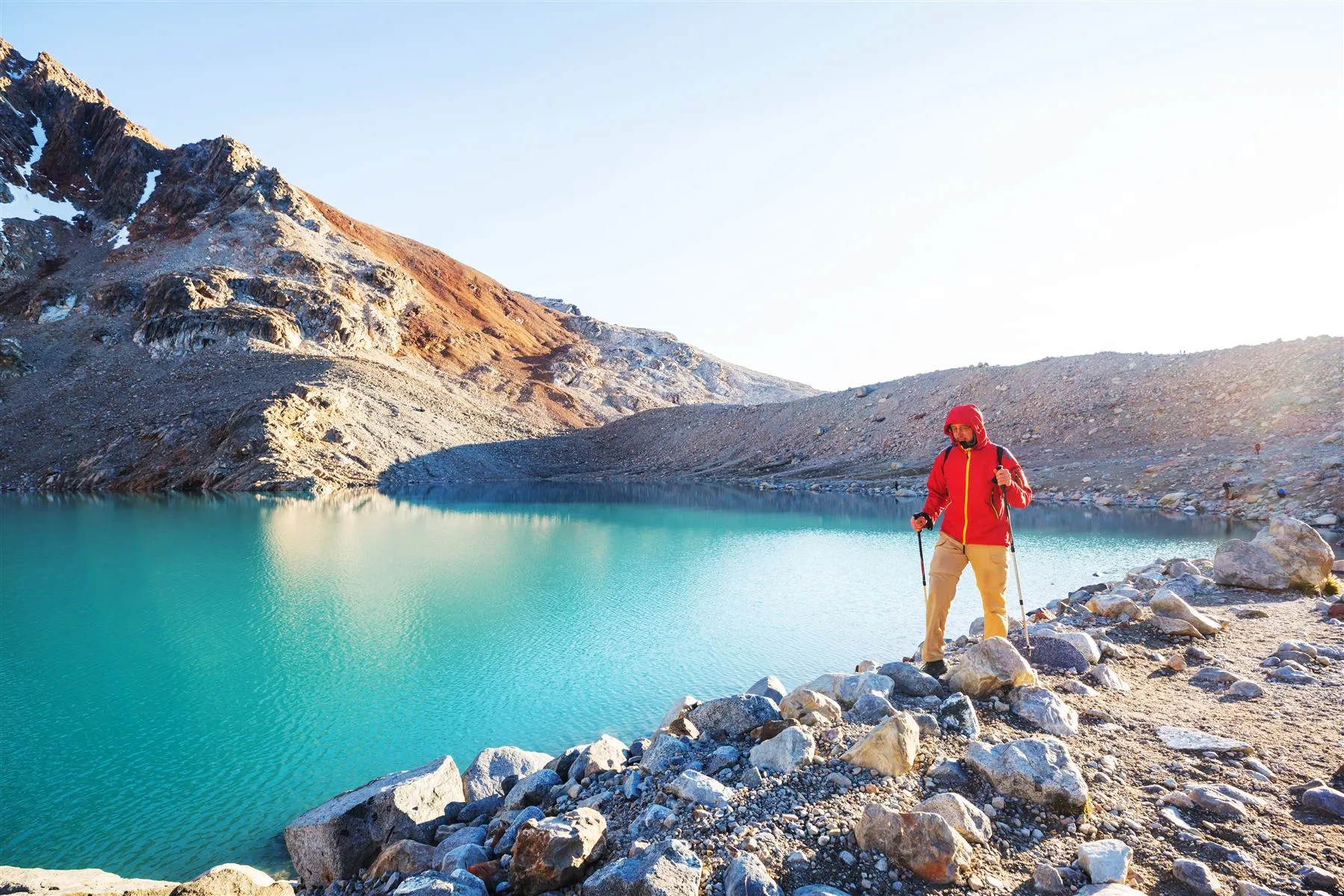 Caminhante junto a uma lagoa glaciar turquesa